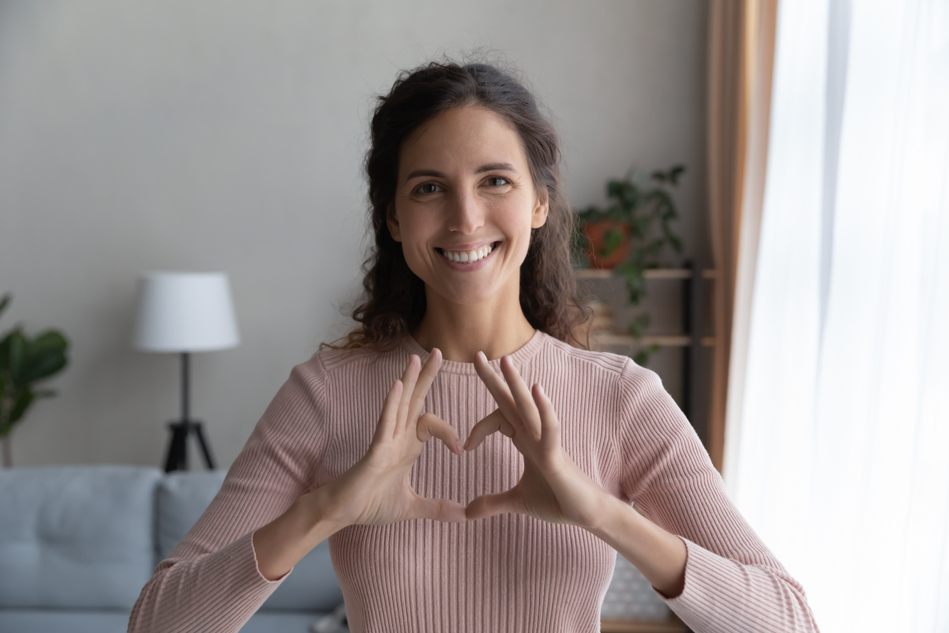 Profile picture of smiling woman show heart gesture with hands